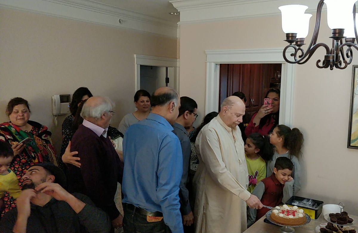 Aslam Hayat cutting his birthday cake at home in Vancouver, surrounded by family
