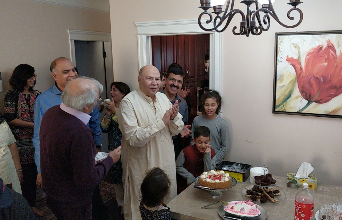 Aslam Hayat with hands together, joyful, at his home birthday celebration