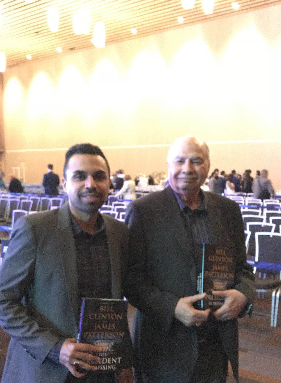 Aslam Hayat holding a copy of The President is Missing at a book event in Vancouver