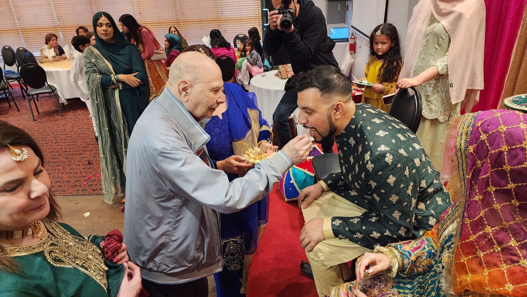 Aslam Hayat feeding sweets to a young man at a family wedding ceremony