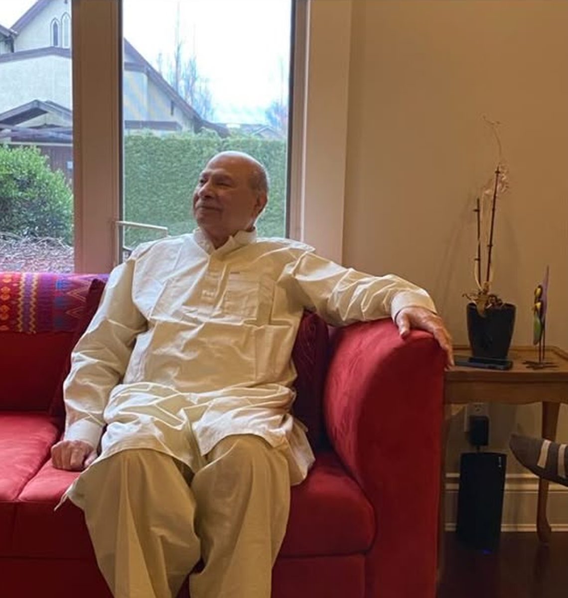 Aslam Hayat relaxed at home in Vancouver, wearing white shalwar kameez