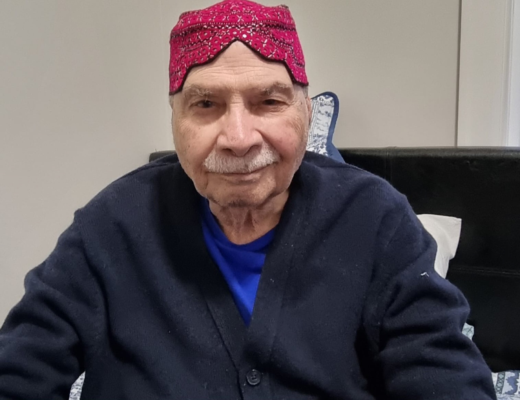 Aslam Hayat wearing a traditional red Sindhi topi, seated at home