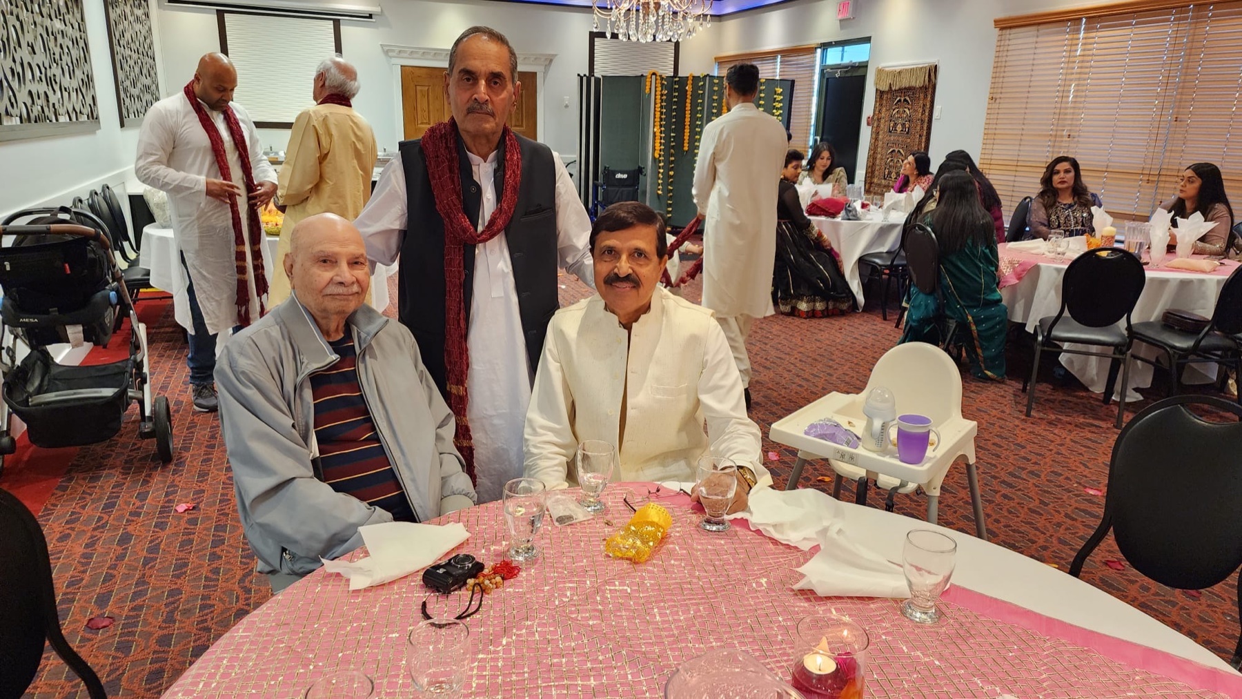 Aslam Hayat seated at a round table with family guests at a wedding event